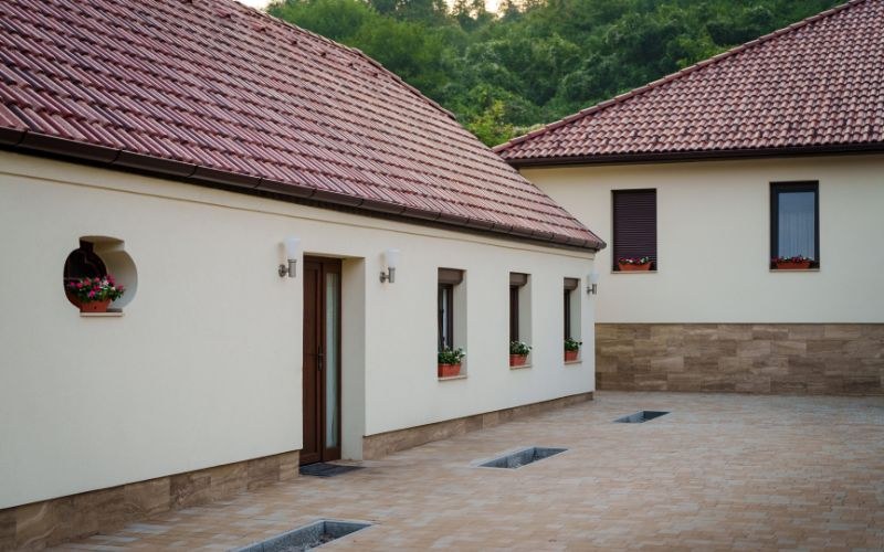 Az udvar a másik irányból: a két szárny találkozása, kerek ablak, virágos ablakpárkányok.