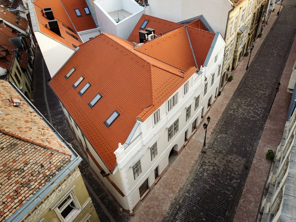 Madártávlati felvétel a felújított cseréptetőről és a belső udvarról, körülötte a belváros háztetői.